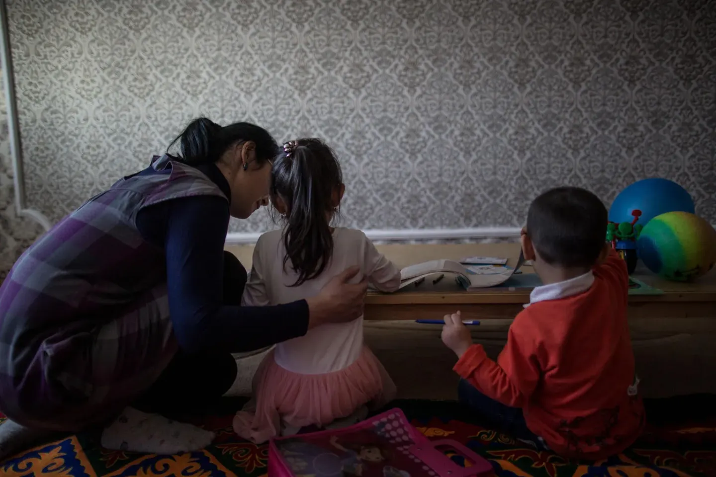 A mother plays with her two children in their apartment.