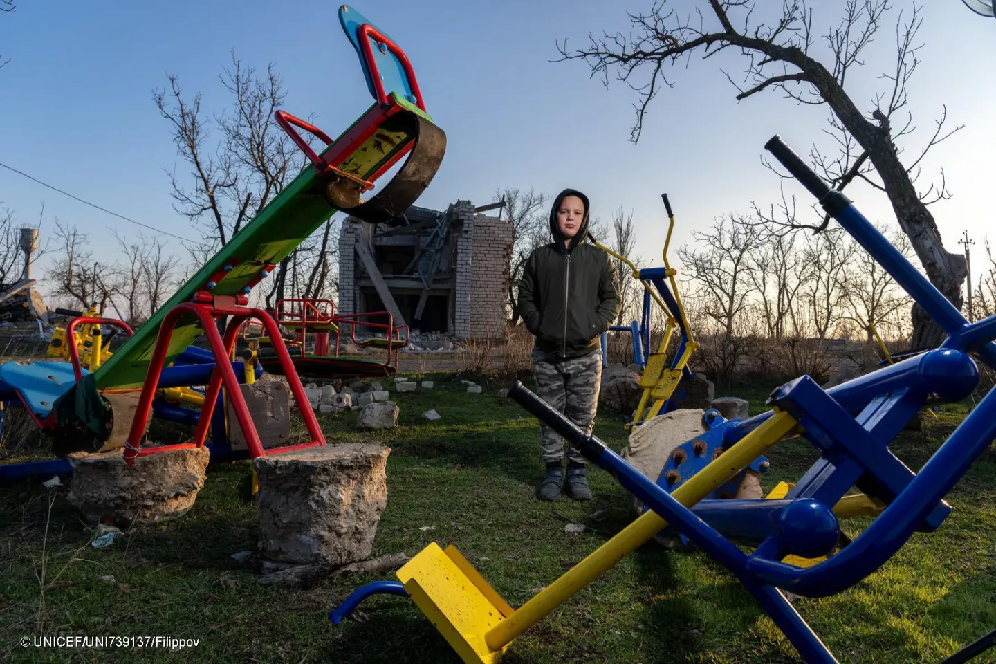 Boy standing in front of the ruins of a kindergarten
