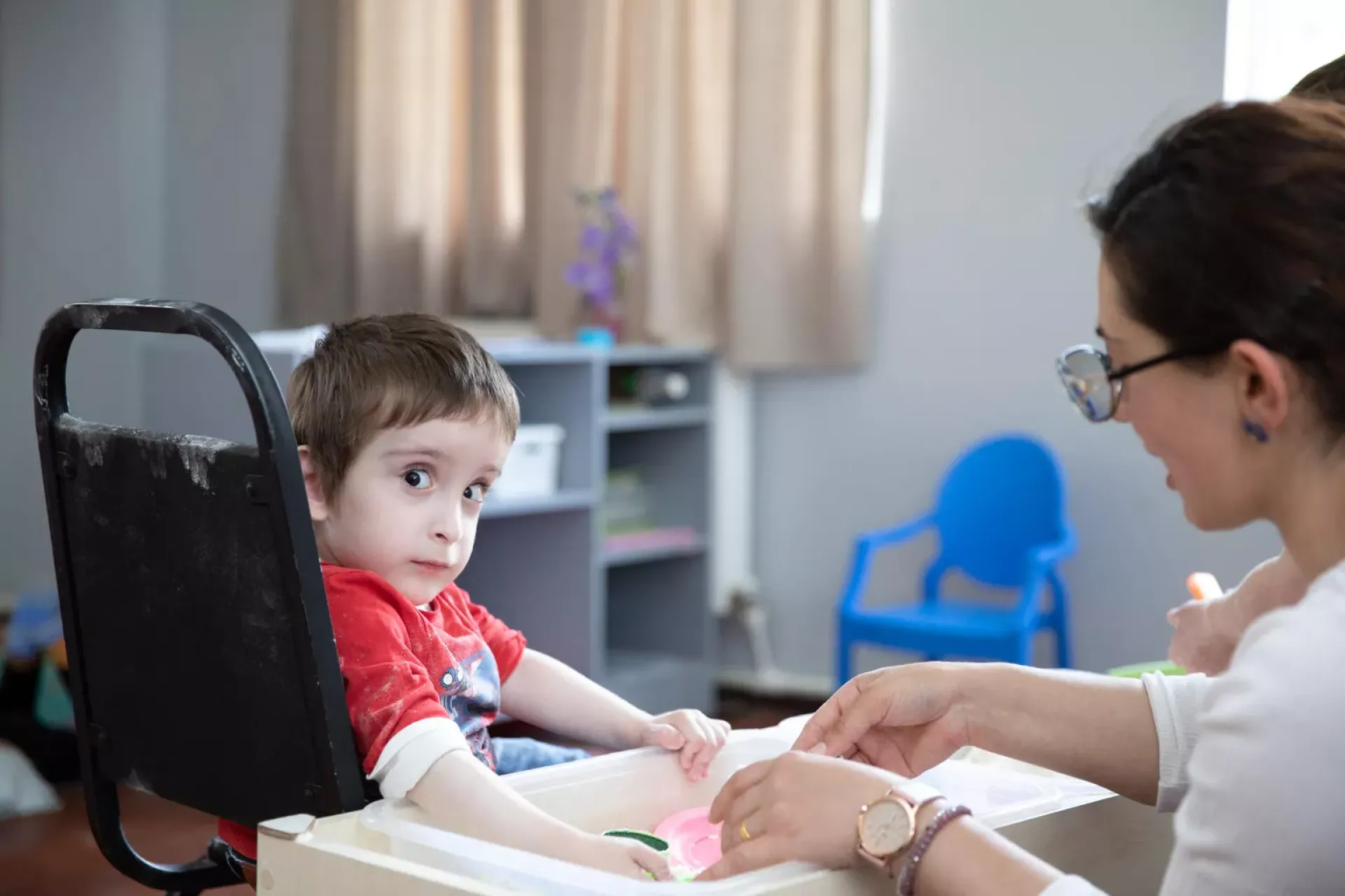 A 4-year-old boy in a wheelchair playing with his kindergarten teacher.
