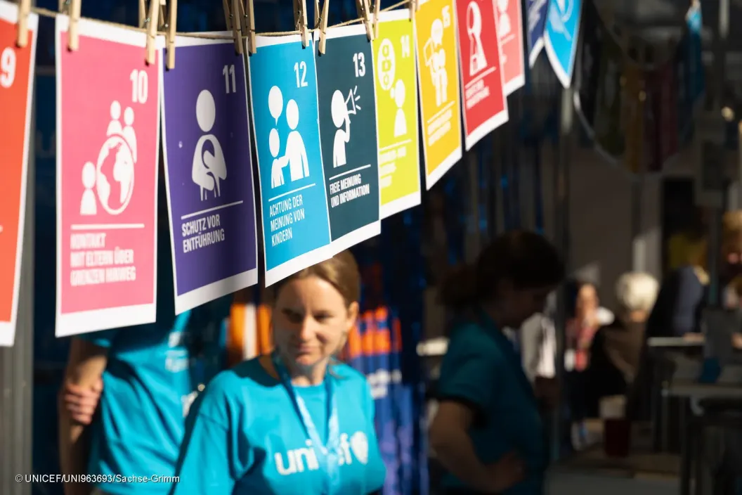 Child standing under SDG bunting.